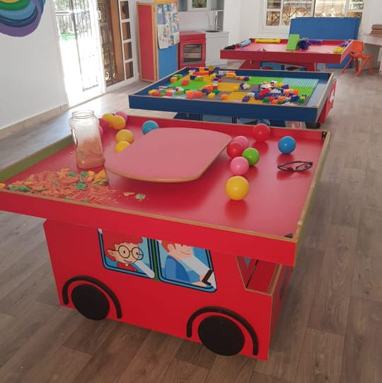 Children's playroom with a red fire truck-shaped table and colorful balls.